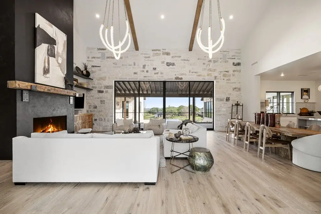 Front elevation of a limestone home with a tile roof, timber entry canopy and three garage bays off a wide concrete drive.
