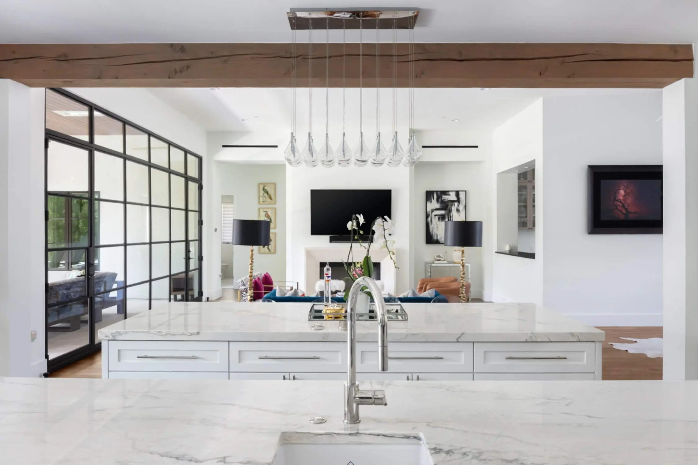 Living room with steel-framed glass partitions, a plaster fireplace and a blue velvet sofa on wide plank floors.