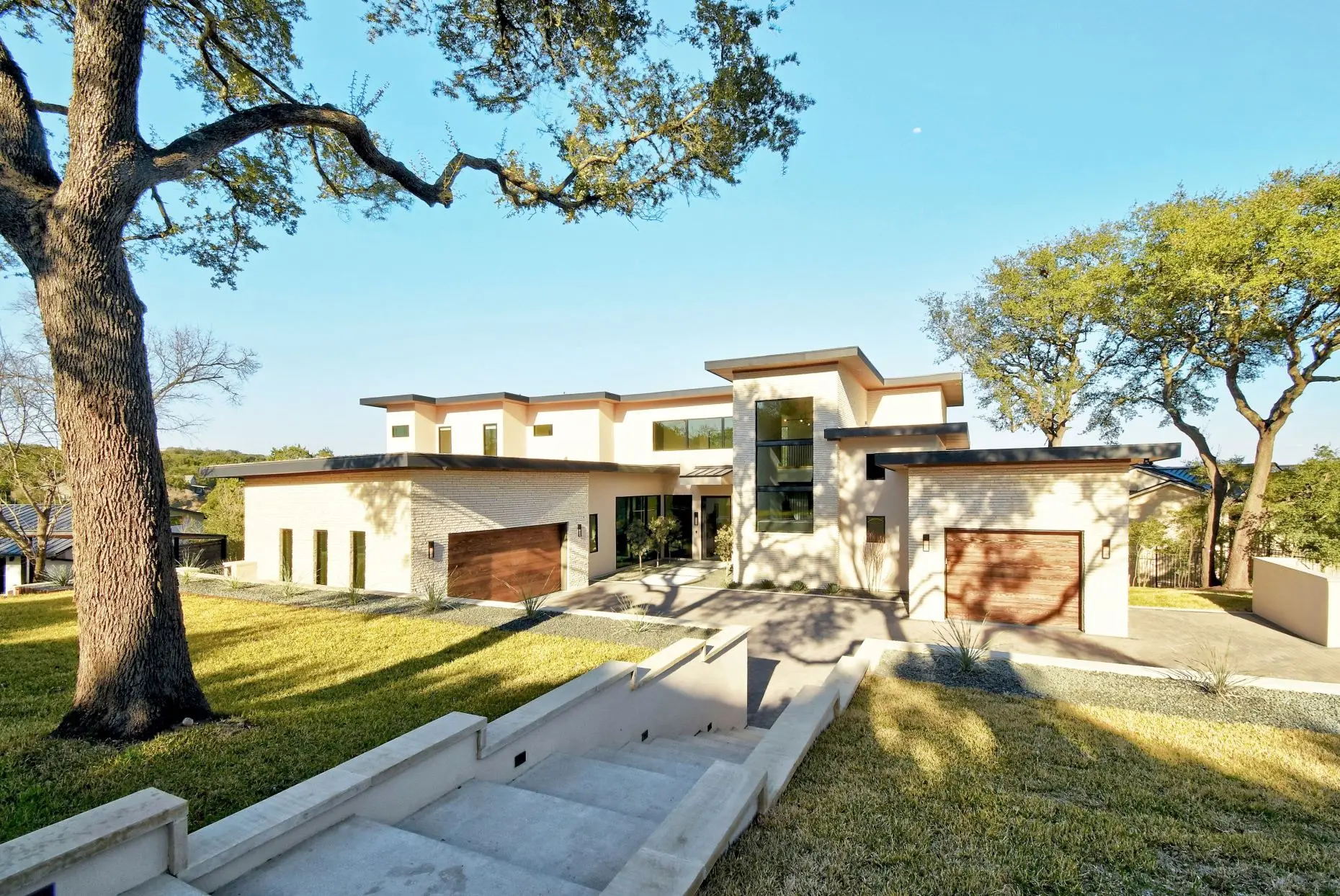 Infinity pool running along the side of a white modern home, looking out over wooded hills.
