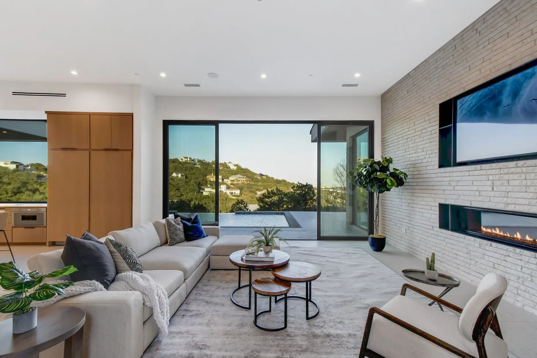 Infinity pool running along the side of a white modern home, looking out over wooded hills.