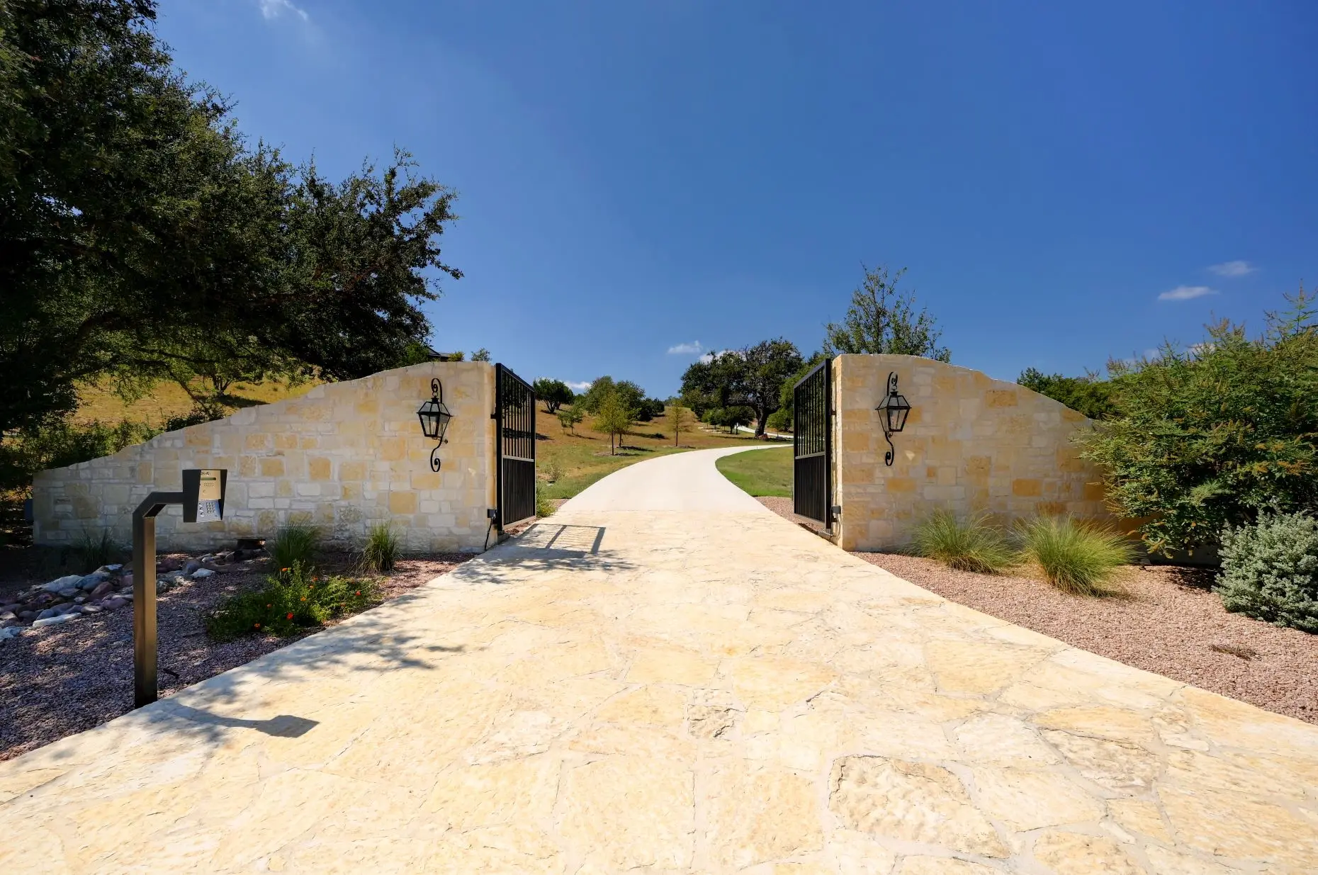 Aerial view of a stone ranch home set around a fountain courtyard, with clipped lawns and open country beyond.