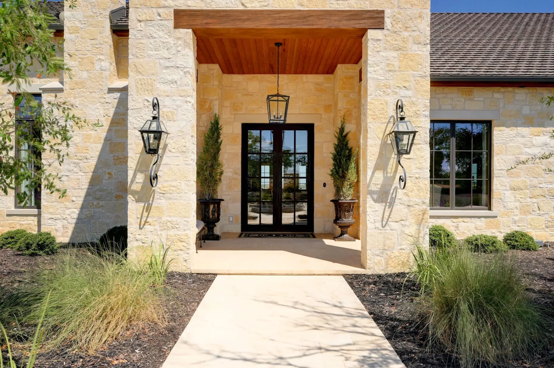 Aerial view of a stone ranch home set around a fountain courtyard, with clipped lawns and open country beyond.