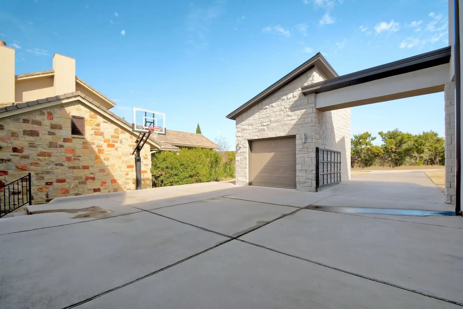 Street elevation of a contemporary home in white stucco and limestone, with black-framed windows and a bare tree in the front yard.