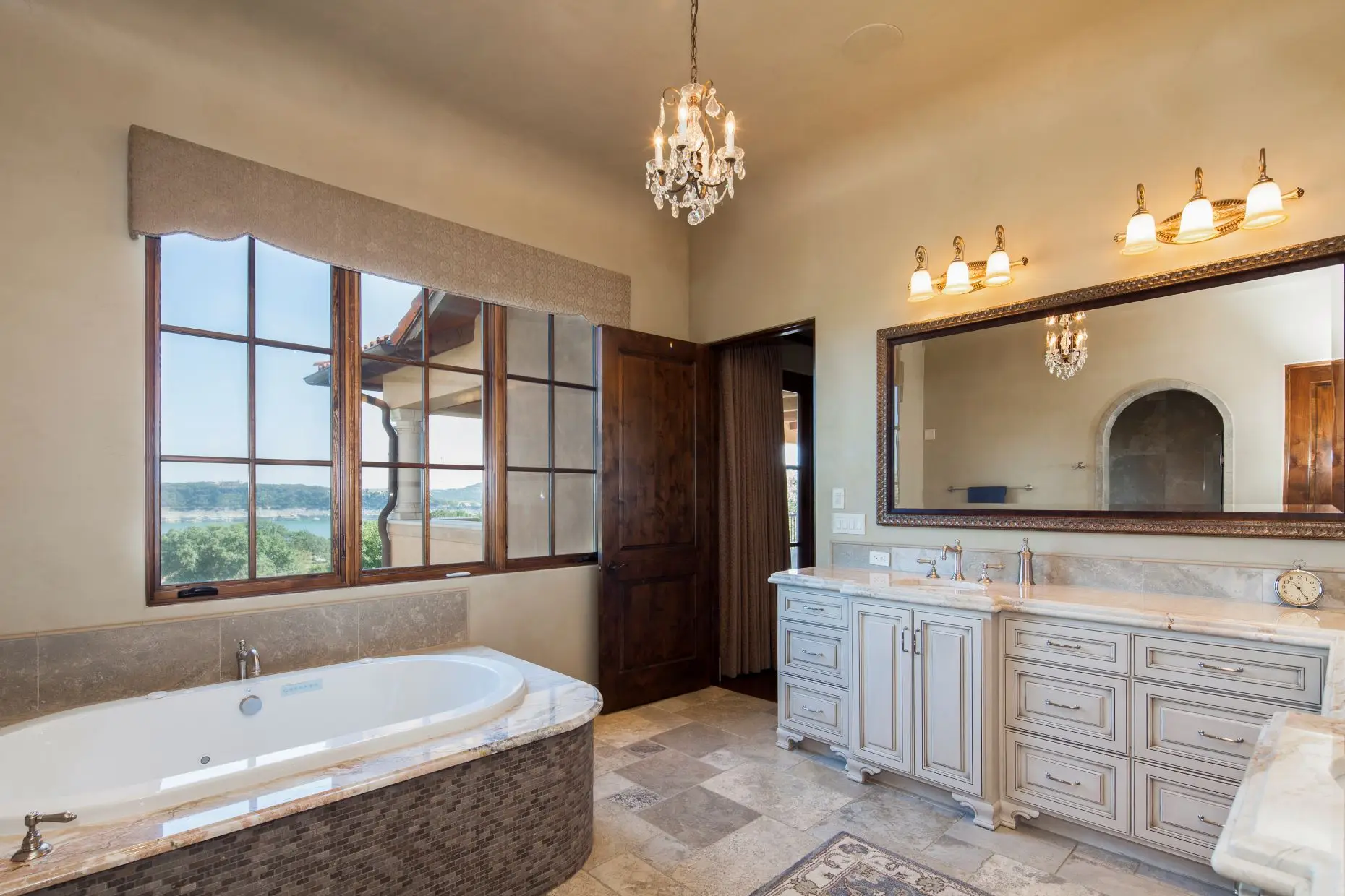 Stone home with a tile roof and arched timber garage doors, around a paved motor court.