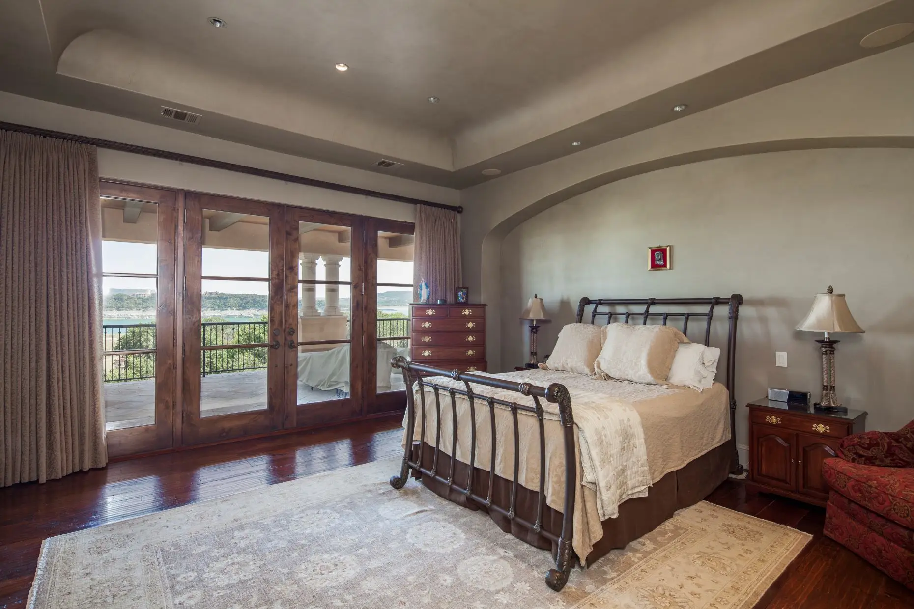 Stone home with a tile roof and arched timber garage doors, around a paved motor court.