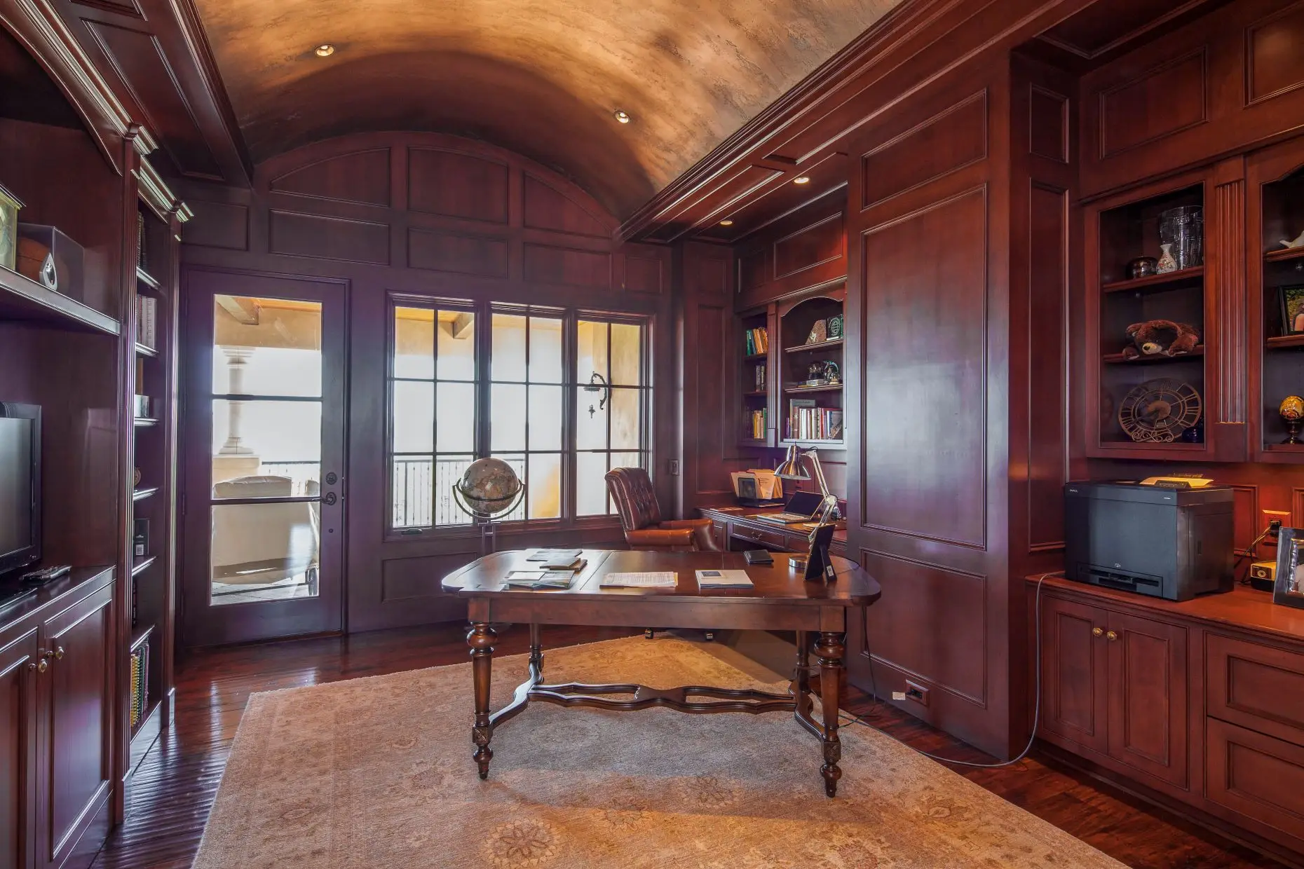 Stone home with a tile roof and arched timber garage doors, around a paved motor court.