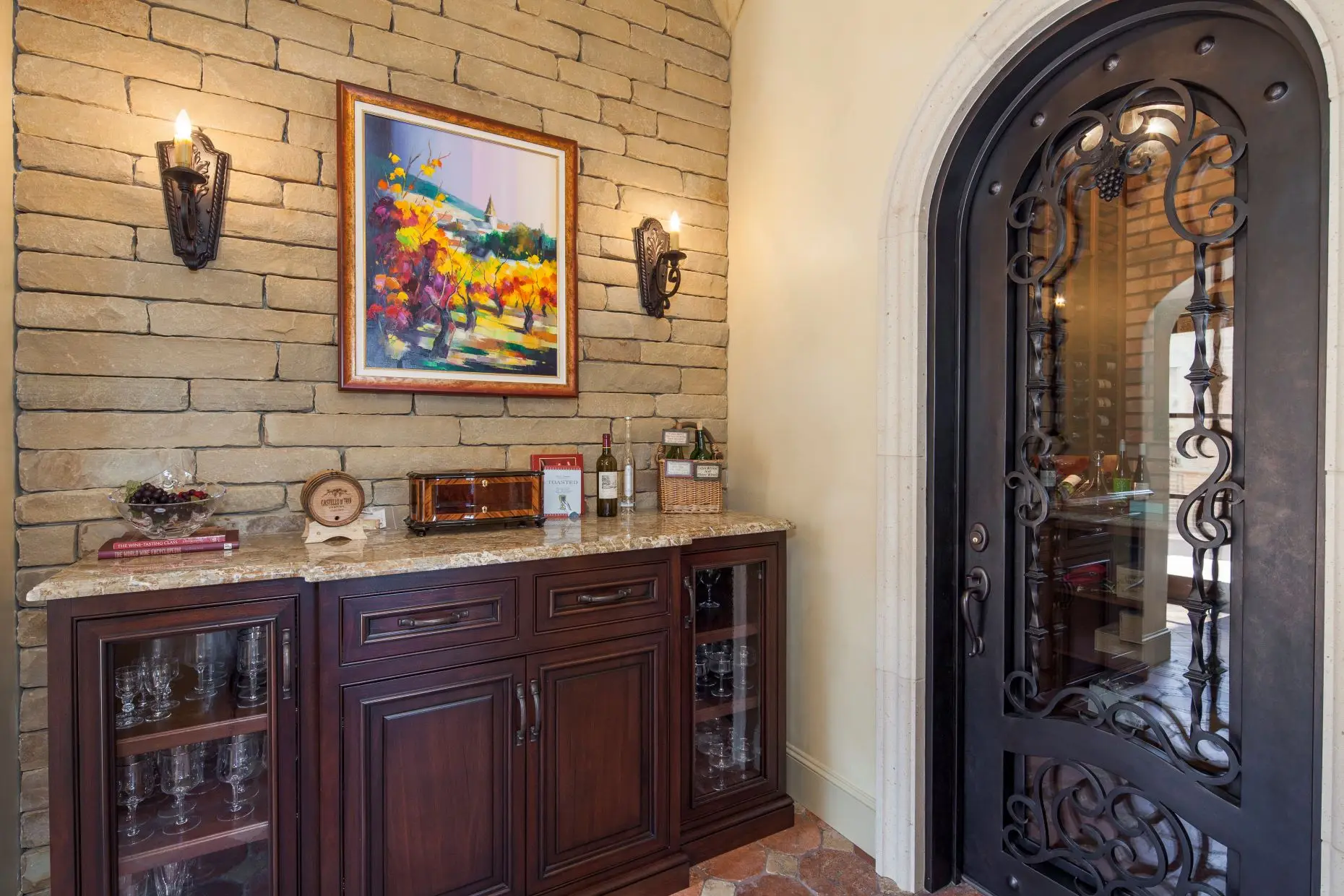 Stone home with a tile roof and arched timber garage doors, around a paved motor court.