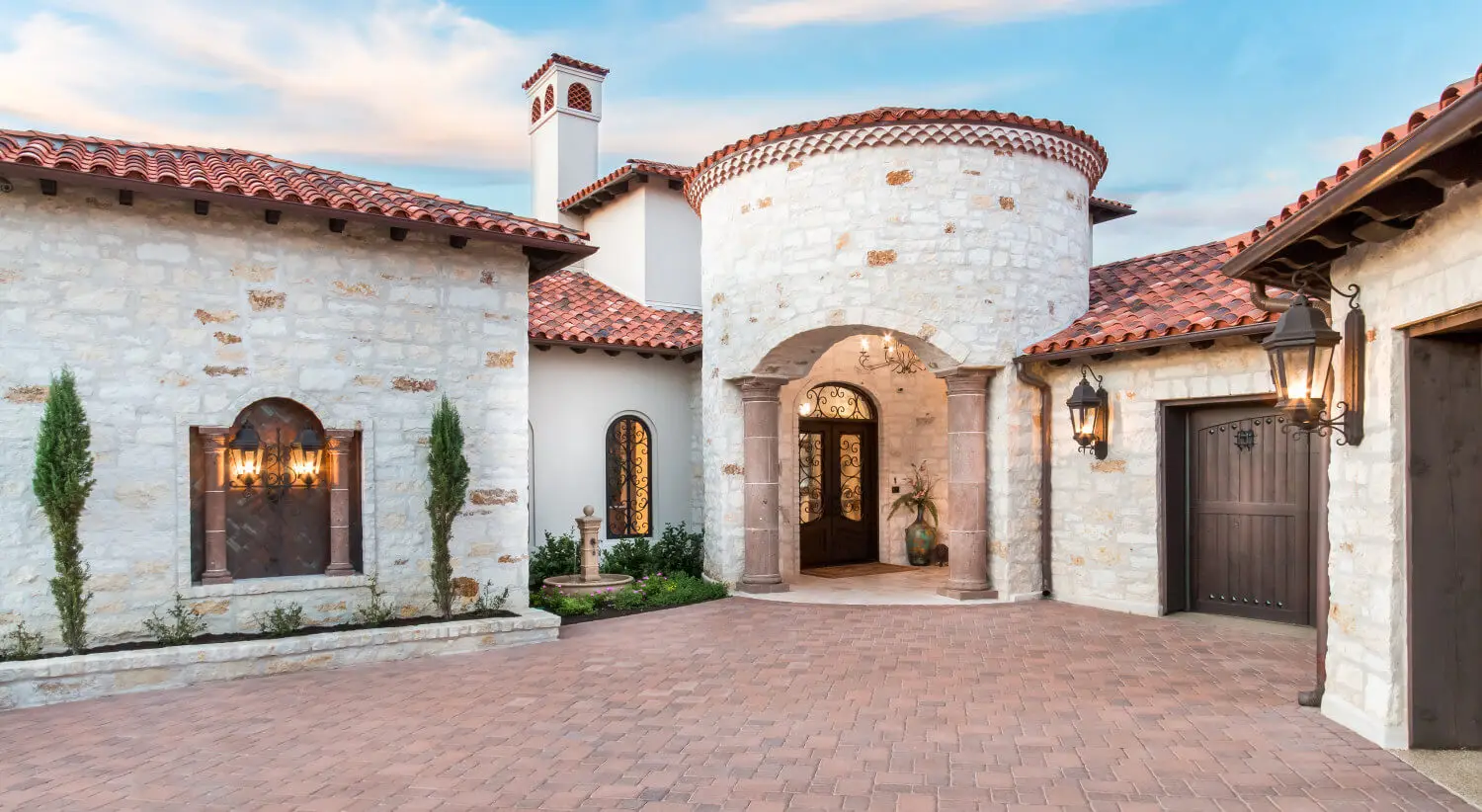 Tuscan-style villa with tile roofs and a stone terrace, seen across still water from the far bank.