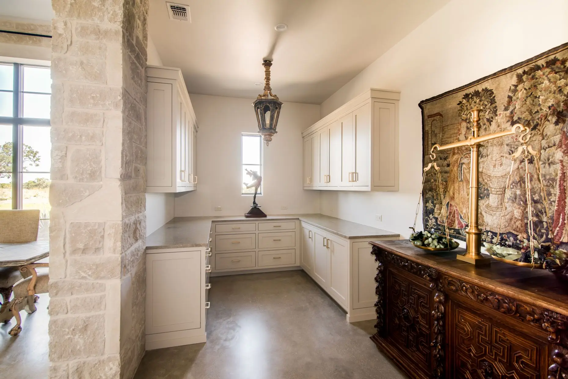 Stone loggia on timber posts running along the rear of the home, above a flagstone terrace set in gravel.