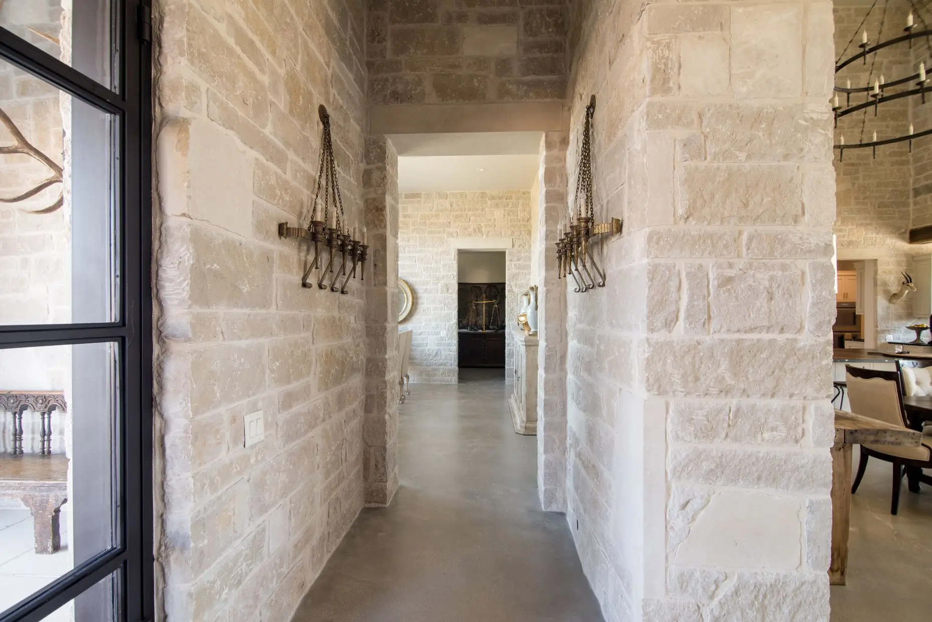 Stone loggia on timber posts running along the rear of the home, above a flagstone terrace set in gravel.