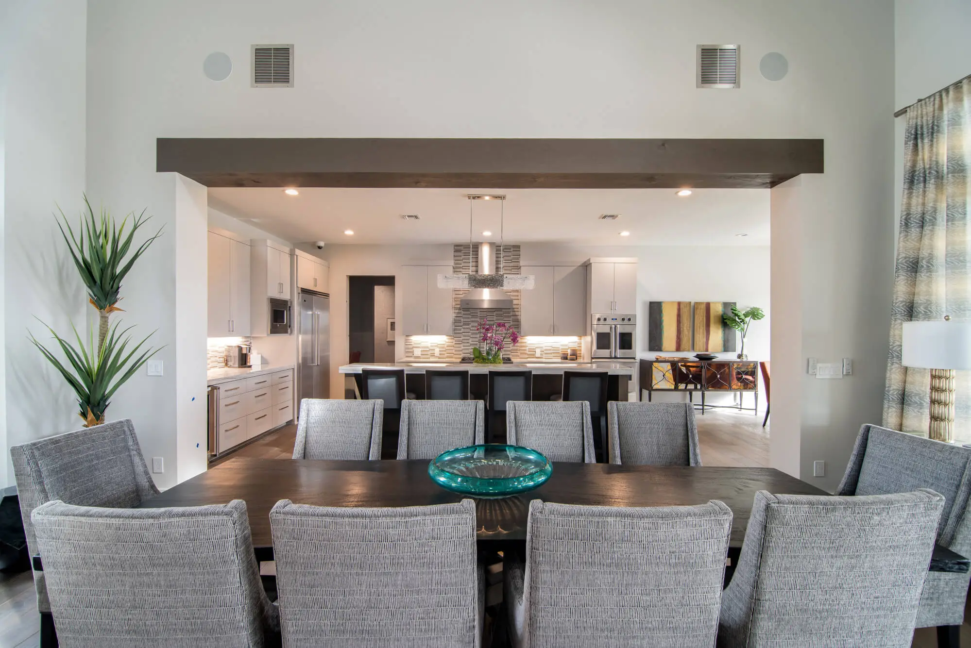 Living room with a full-height stone fireplace, exposed beams and a glass door standing open to the view beyond.