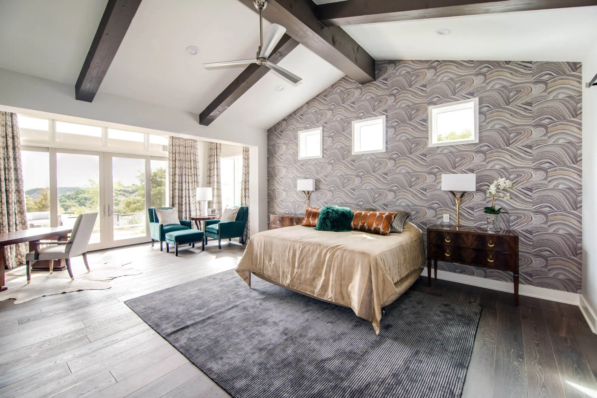 Living room with a full-height stone fireplace, exposed beams and a glass door standing open to the view beyond.