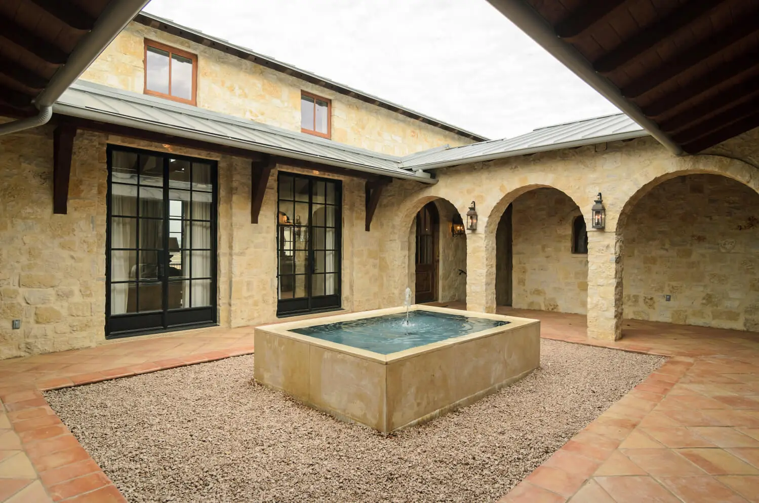 Limestone home stepping up a terraced slope, with a tall chimney and stacked stone retaining walls.